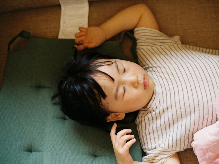 Anak laki-laki tidur siang di atas kasur hijau