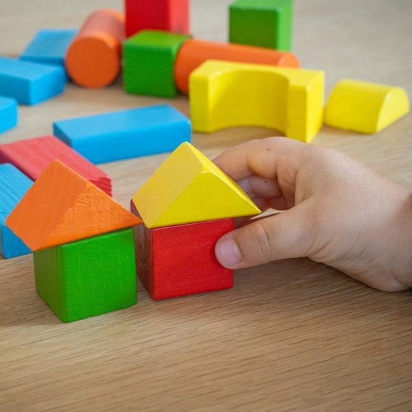 Tangan anak menyusun balok kayu warna-warni