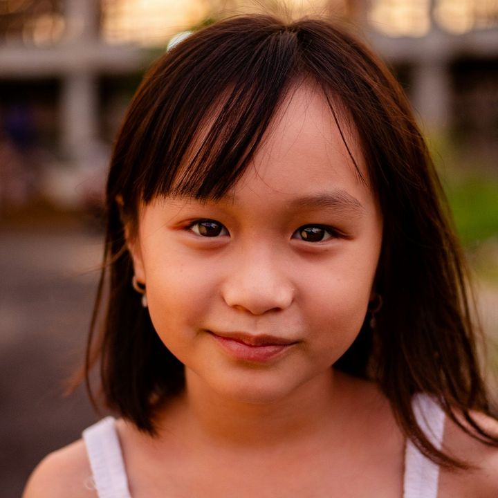 Anak perempuan berponi tersenyum ke kamera
