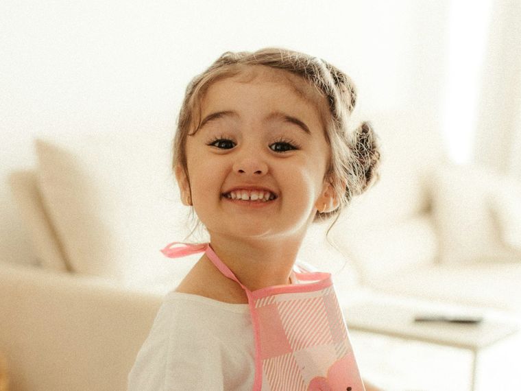 Anak perempuan bercelemek tersenyum di dapur