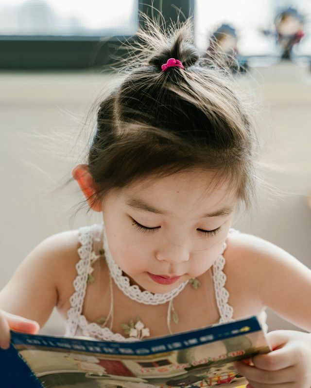 Anak perempuan membaca buku bergambar