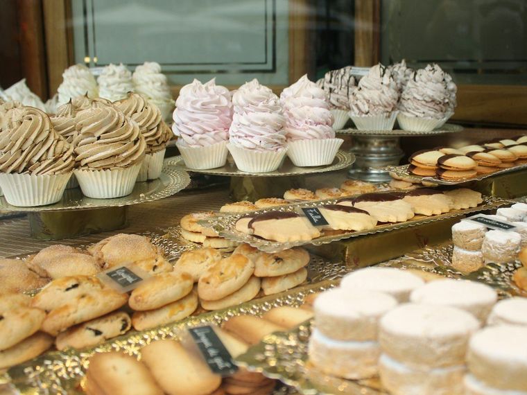 Etalase kaca berisi cupcake, meringue, dan kue kecil