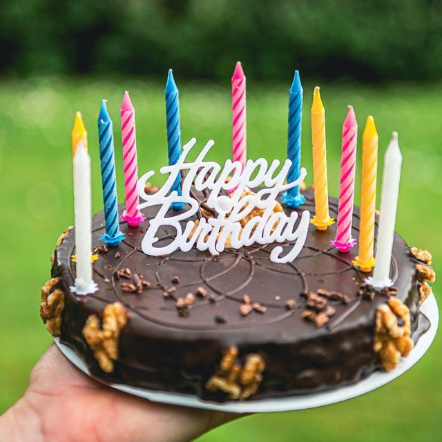 Kue cokelat dengan lilin warna-warni dan hiasan Happy Birthday