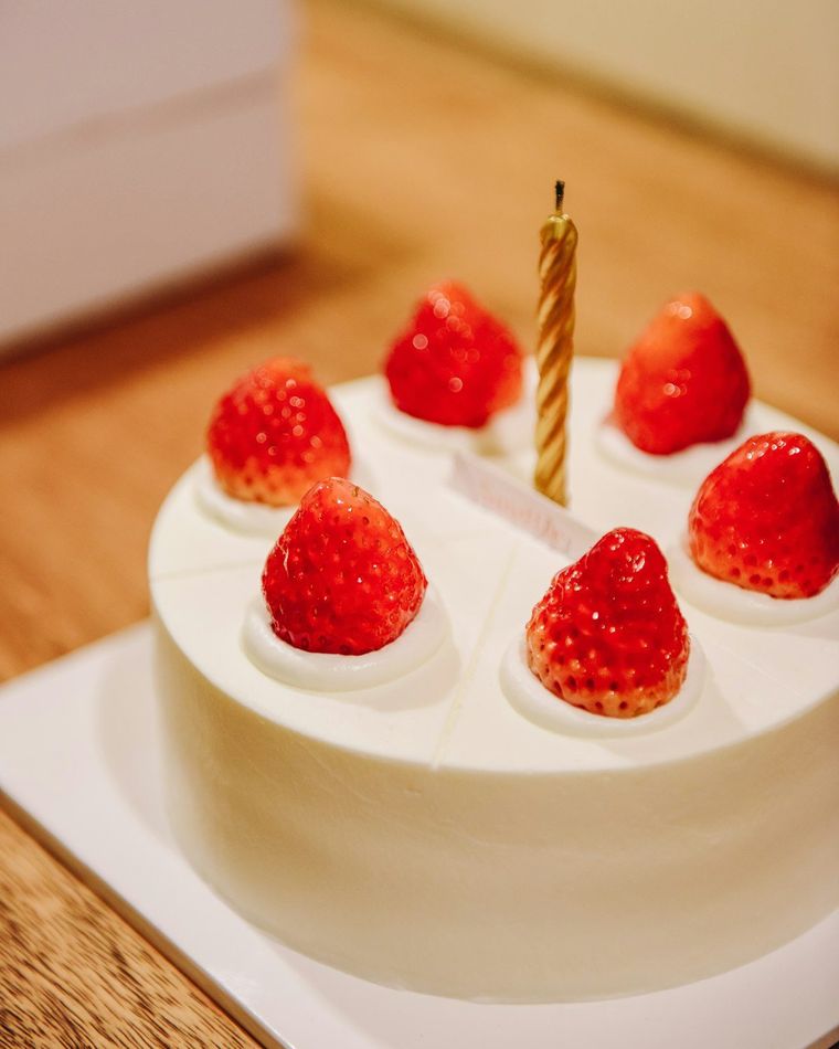 Kue krim putih dengan stroberi dan satu lilin di atasnya
