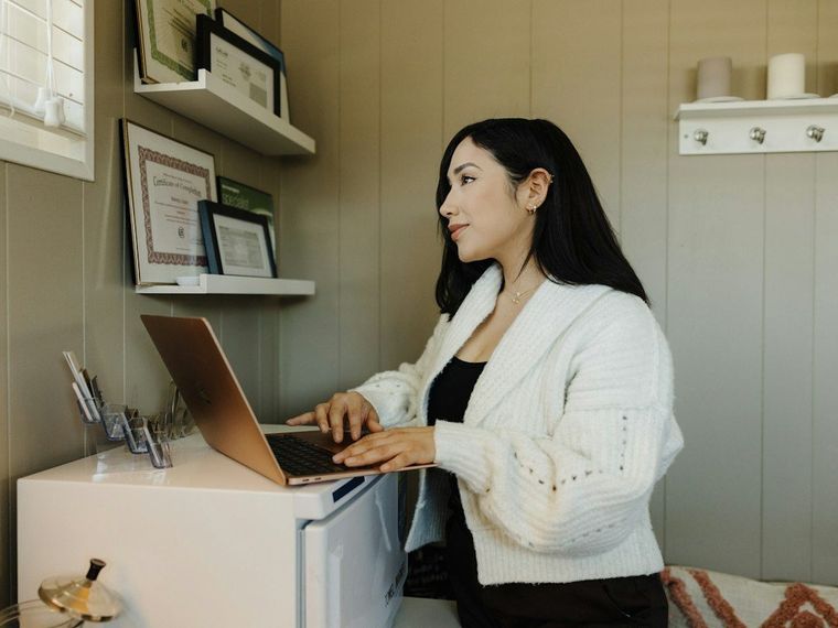 Pemilik usaha mengetik di laptop di dekat jendela